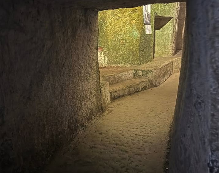 A hand-cut tuff passage opening onto a lit chamber